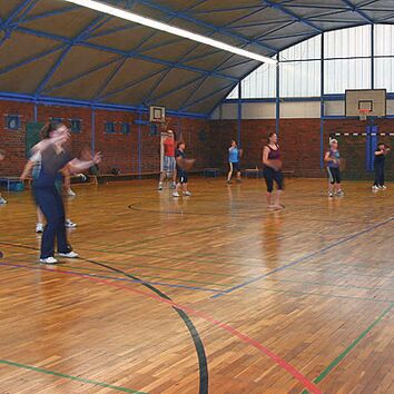 eine Gruppe Menschen beim Zumba in einer Turnhalle